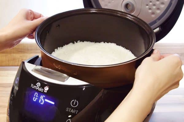 Hands liftin cookd rice rom black Sakura rice cooker with cooked rice