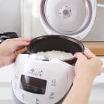 Hands lifting cooked rice from Panda rice cooker