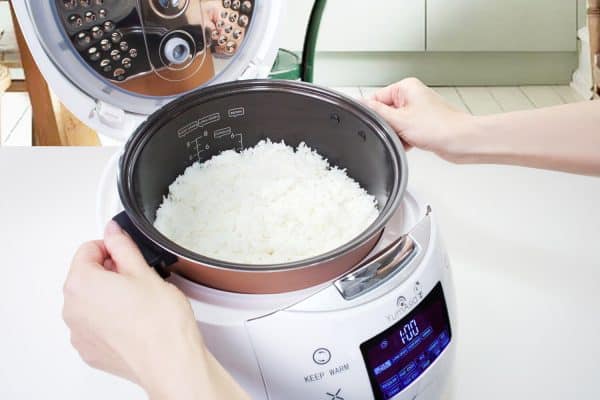 Hanads lifting Ninja ceramic bowl from Sakura white rice cooker